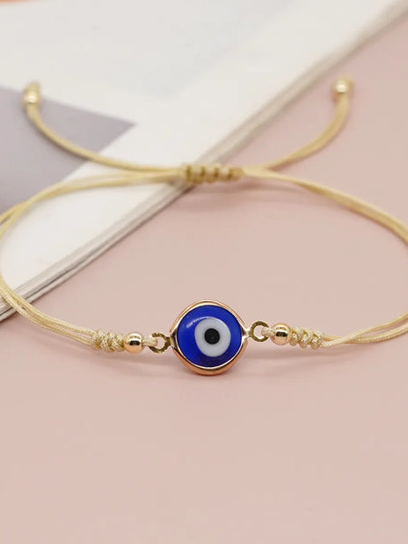 Blue evil eye bracelet with double gold tone cord and round beads, shown at an angle