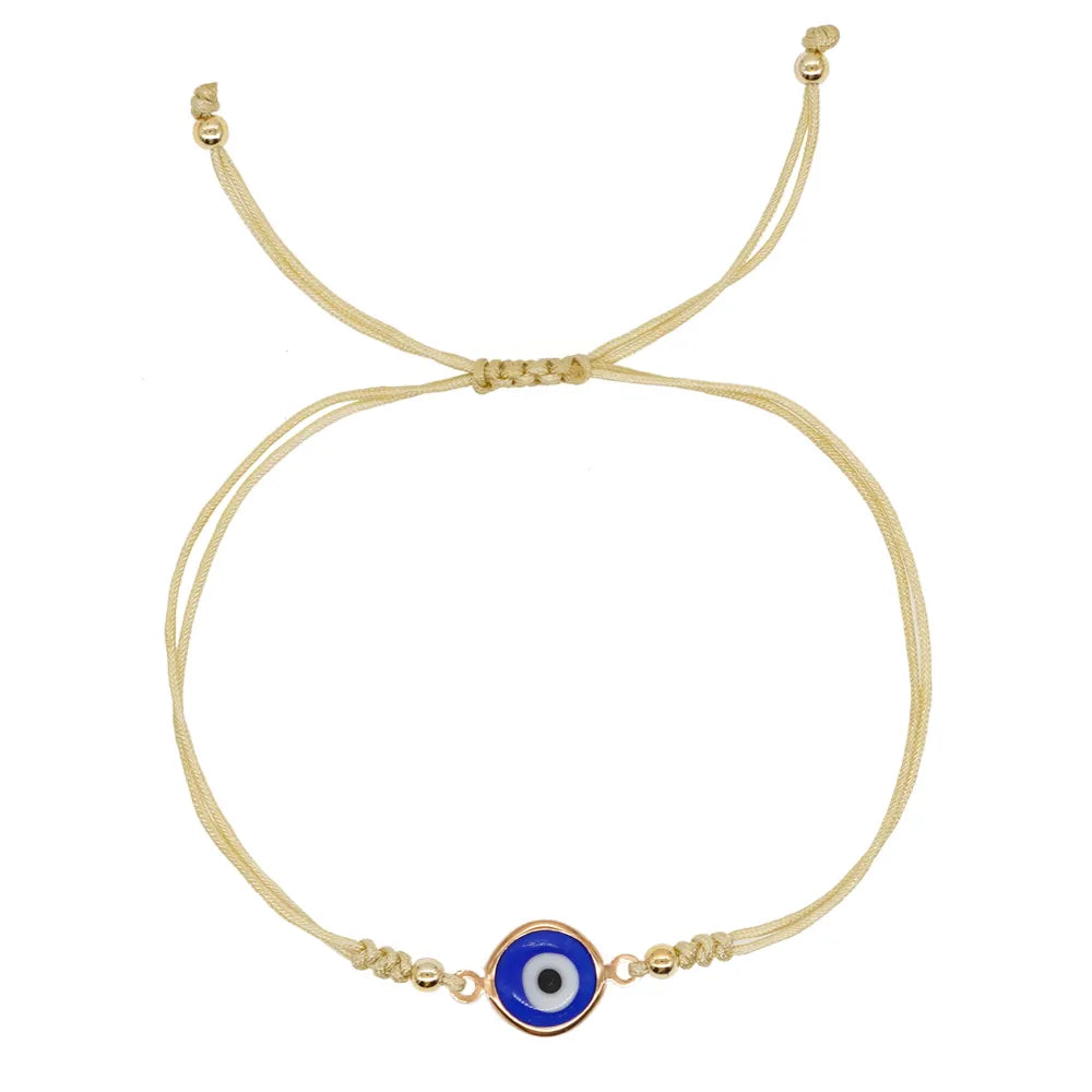 Blue evil eye bracelet with double gold tone cord and beaded tails on a white background
