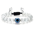 Translucent white round beads surrounding a blue eye, with silver tone accents and knotted black cord