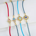 Four braided bracelets showing Hamsa and sunburst eye centerpieces with red, light blue, and navy and turquoise cords