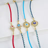 Four braided bracelets showing Hamsa and sunburst eye centerpieces with red, light blue, and navy and turquoise cords