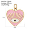 Pink heart charm with a white eye, black pupil and radiating gold tone lash details, shown with measurement annotations