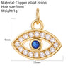Gold tone open eye charm with a blue center, clear border accents and an attached top ring, shown with measurement annotations
