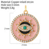 Pink disc evil eye charm with a turquoise center, black curved details, gold tone rays and clear accents, shown with annotations