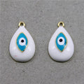 Two white teardrop evil eye charms with turquoise eye motifs and gold tone loops