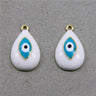 Two white teardrop evil eye charms with turquoise eye motifs and gold tone loops