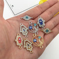 Almond eye, Hamsa and floral circle connectors with gold tone and silver tone frames resting on a palm.