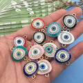 Oval Evil Eye connectors in multiple colors held against a blue and green background.