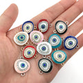 Twelve colorful oval Evil Eye connectors with clear accents and paired loops resting on a palm.