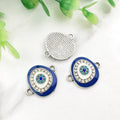 Blue oval Evil Eye connectors with silver tone frames, showing decorated fronts and a grooved back.