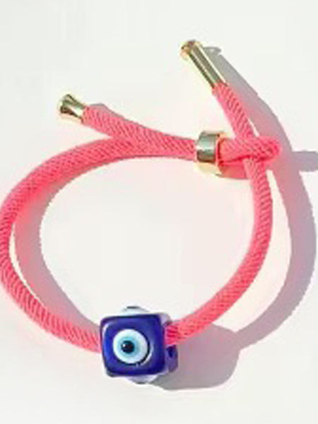 Coral pink cord bracelet with a dark blue cube evil eye bead and gold tone end caps