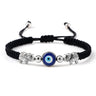 Black cord bracelet with a blue eye between two patterned silver tone elephants