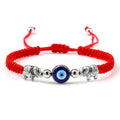 Red cord bracelet with a blue eye between two inward-facing silver tone elephants