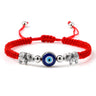 Red cord bracelet with a blue eye between two inward-facing silver tone elephants