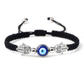 Black cord bracelet with a round blue eye flanked by two dotted silver tone Hamsas
