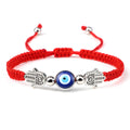 Red cord bracelet with a round blue eye flanked by two dotted silver tone Hamsa hands