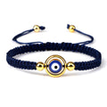 Blue cord bracelet with an open gold tone circular frame surrounding the blue eye