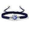 Blue knotted cord bracelet with a blue eye inside an open silver tone circular frame