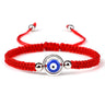 Red knotted cord bracelet with a blue eye inside an open silver tone circular frame