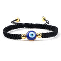 Black knotted cord bracelet with one blue eye between two gold tone beads