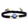 Black knotted cord bracelet with one blue eye between two gold tone beads