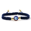 Blue knotted cord bracelet with a round blue eye and gold tone beads