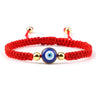 Red knotted cord bracelet with one round blue eye and gold tone beads