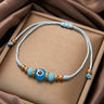 Turquoise evil eye cord bracelet with pale blue cord, faceted side beads and gold tone spacers