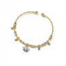 Gold tone eyelash eye open cuff bracelet on white, with clear rectangular accents and four small dangling blue eye charms.