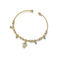 Gold tone Hamsa hand open cuff bracelet on white, with clear accents, a blue eye and four small dangling eye charms.