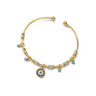 Gold tone round eye open cuff bracelet on white, with concentric blue and clear accents and four small dangling eye charms.