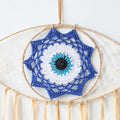Close-up of the blue, white, turquoise and black eye motif inside a tan dream catcher frame