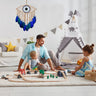 Tan eye-shaped dream catcher with blue feathers displayed on a wall beside a play tent