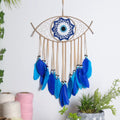 Tan eye-shaped dream catcher with a blue eye center and blue and turquoise feather fringe