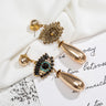 Gold tone evil eye earrings showing one detailed front and one textured reverse with a straight post