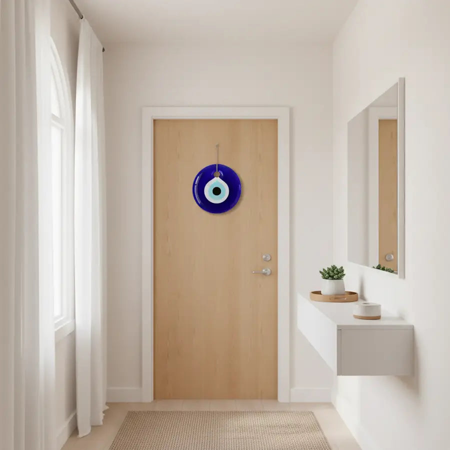 Blue evil eye wall hanging facing the front door in a bright, uncluttered apartment entryway