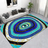 Rectangular evil eye floor mat with blue and turquoise rings, gold tone dots and geometric borders beside a white sofa.