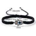 Black braided Hamsa bracelet with measurement annotations around the band, hand charm and eye