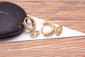 Multicolored evil eye charm hoops with one hoop open to show its curved post and hinged closure