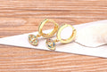 Angled side view of gold tone hoops with multicolored eye charms and plain rear bands