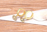Angled side view of gold tone hoops with multicolored eye charms and plain rear bands
