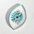 Turquoise sunburst eye tray holding rings and earrings, viewed at an angle