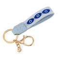 Light blue loop keychain with three almond-shaped blue eye motifs, white borders and gold tone attachments.