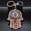 Brown Hamsa keychain with green flowers and a blue Evil Eye, displayed front-facing with its keyring and clasp above.