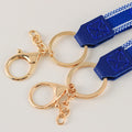 Close-up of gold tone split rings, lobster clasps and short link chains attached to blue strap tabs.