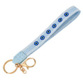 Light blue loop keychain with round blue eye motifs, white borders, a gold tone ring and lobster clasp.