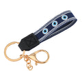 Navy loop keychain with three round eye motifs, white borders, a black tab and gold tone attachments.