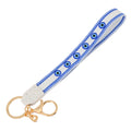 White loop keychain with six round blue eye motifs, blue patterned borders and gold tone attachments.