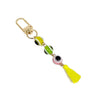 Multicolored evil eye keychain with yellow, green and pink beads, a yellow tassel and a gold tone clip on white.