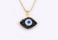 Black eye-shaped pendant with a blue and white center and gold tone border and chain against a white background.